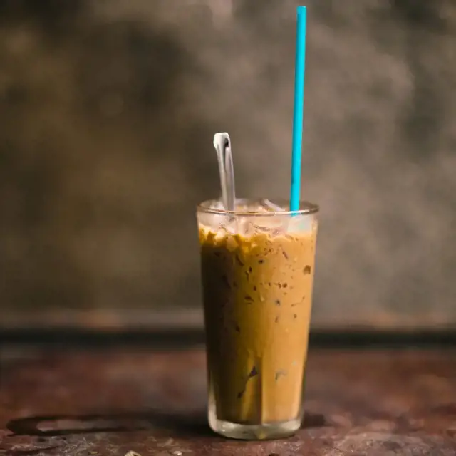 vietnamese iced coffee known as Cafe Sua Da in a glass with green straw