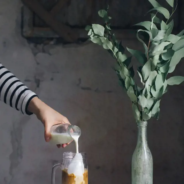 Pour your oat milk in your vegan iced coffee